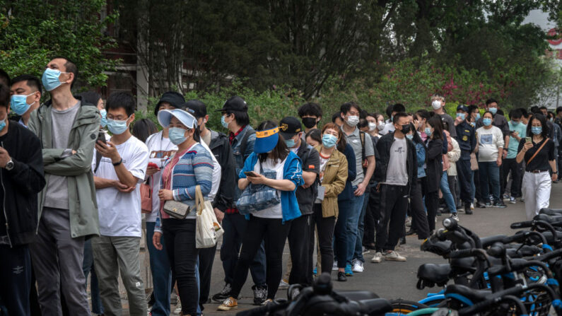 La gente hace fila para someterse a las pruebas de ácido nucleico para detectar el COVID-19 en un centro de pruebas improvisado en el distrito de Chaoyang el 25 de abril de 2022 en Beijing, China. (Kevin Frayer/Getty Images)