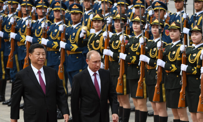 El presidente de Rusia, Vladímir Putin (C), pasa revista a una guardia de honor militar junto al líder chino, Xi Jinping (iz), durante una ceremonia de bienvenida frente al Gran Salón del Pueblo en Beijing, el 8 de junio de 2018. (Greg Baker/POOL/AFP vía Getty Images)