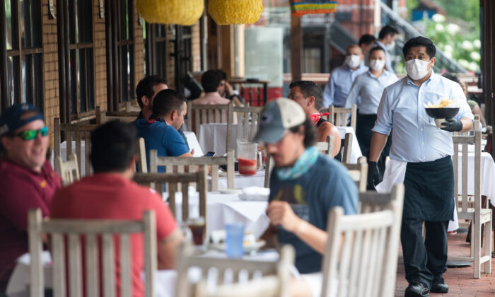 Un camarero con mascarilla y guantes entrega la comida en una mesa a los clientes sentados en un patio exterior de un restaurante mexicano en Washington, DC, el 29 de mayo de 2020. (Saul Loeb/AFP vía Getty Images)