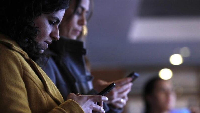 Fotografía de archivo de dos personas que utilizan su teléfono móvil. EFE/Paolo Aguilar