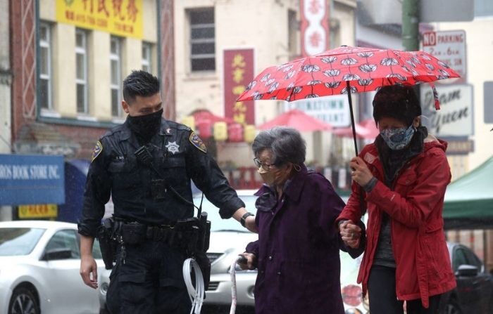  El oficial de policía de San Francisco William Ma (I) ayuda a una anciana a cruzar la calle mientras realiza una patrulla a pie en el barrio chino el 18 de marzo de 2021 en San Francisco, California. (Justin Sullivan/Getty Images)