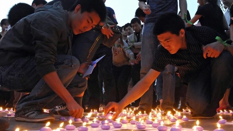 Voluntarios chinos encienden velas en la Plaza Conmemorativa del Terremoto de Tangshan durante una ceremonia en memoria de las víctimas del terremoto de Sichuan el 21 de mayo de 2008. (Simon Lim/AFP/Getty Images)