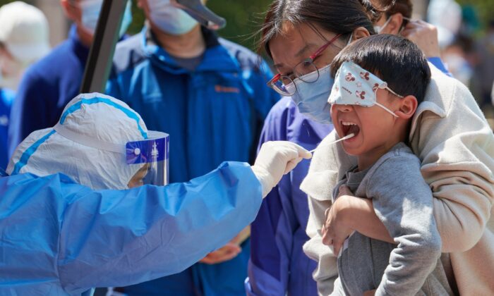 Un niño recibe una prueba de hisopo para COVID-19 en un recinto durante un cierre en el distrito de Pudong, en Shanghái, China, el 17 de abril de 2022. (Liu Jin/AFP a través de Getty Images)
