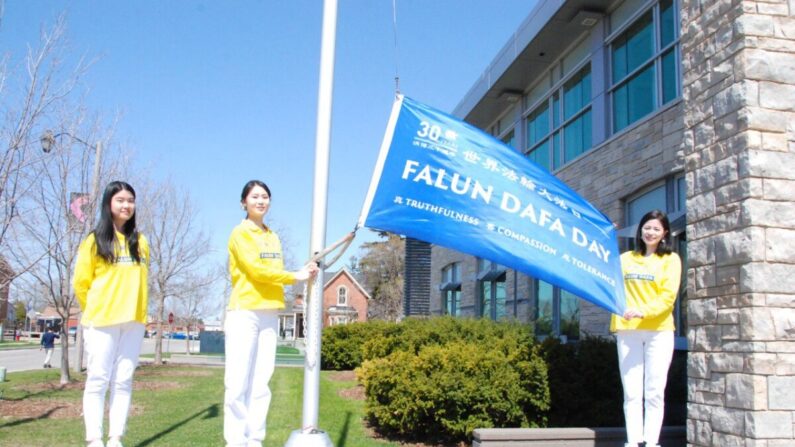 Practicantes de Falun Dafa izan una bandera en celebración del 30º aniversario de la difusión de la práctica espiritual, en la ciudad de Milton, Ontario, el 29 de abril de 2022. (Arek Rusek/The Epoch Times)
