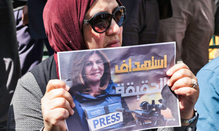 Los palestinos sostienen carteles en los que se ve a la veterana periodista de Al Jazeera Shireen Abu Akleh, que recibió un disparo mortal mientras cubría una redada en el campo de refugiados de Yenín, en la ciudad cisjordana de Hebrón, el 11 de mayo de 2022. (Hazem Bader/AFP vía Getty Images)