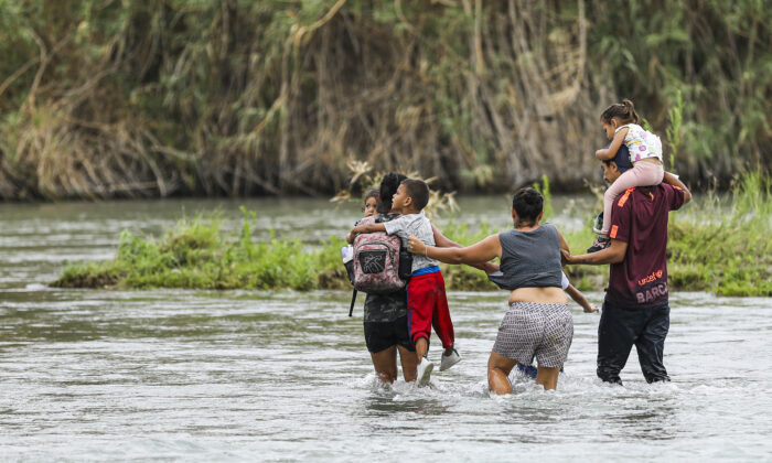 Un grupo de hondureños cruza el Río Grande hacia Eagle Pass, Texas, desde Piedras Negras, México, el 21 de abril de 2022. (Charlotte Cuthbertson/The Epoch Times)