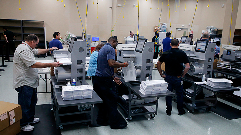 El personal electoral carga las boletas en las máquinas mientras comienza el recuento en la Oficina del Supervisor de Elecciones del Condado de Broward en Lauderhill, Florida, el 11 de noviembre de 2018. (Joe Skipper/Getty Images)
