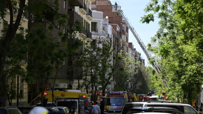 Un bombero inspecciona un edificio desde una escalera, mientras los servicios de emergencia buscan a dos personas desaparecidas después de que una fuerte explosión hiriera a 18 personas en el barrio de Salamanca, en Madrid (España), el 6 de mayo de 2022. (Pierre-Philippe Marcou/AFP vía Getty Images)