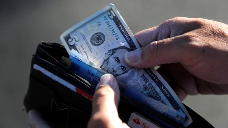 Una persona guarda en su cartera un billete de cinco dólares en Tepatitlán, estado de Jalisco (México). EFE/ Francisco Guasco