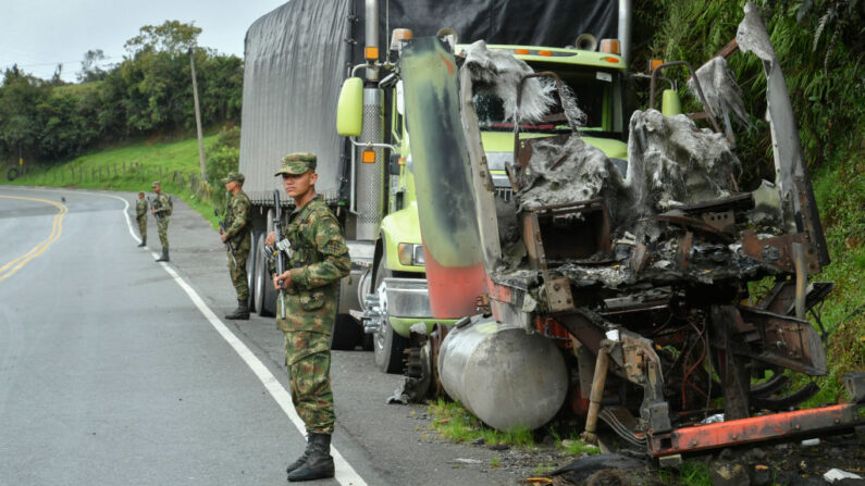 Soldados hacen guardia junto a un camión quemado por miembros del cártel de la droga Clan del Golfo, en una carretera cerca de Yarumal, departamento de Antioquia, Colombia, el 6 de mayo de 2022. (Joaquin Sarmiento/AFP vía Getty Images)