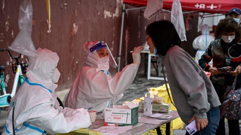 Un trabajador sanitario toma una muestra con un hisopo a una mujer para analizar el COVID-19 en un centro de análisis improvisado en Beijing el 27 de abril de 2022. (Jade Gao/AFP vía Getty Images)
