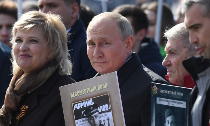 El presidente ruso Vladimir Putin y otros participantes llevan retratos de sus familiares, en el centro de Moscú, el 9 de mayo de 2022. (Natalia Kolesnikova/AFP vía Getty Images)
