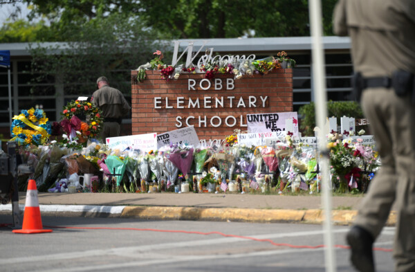 Los policías estatales de Texas colocan flores traídas por los lugareños en el monumento improvisado de la Escuela Primaria Robb el 27 de mayo de 2022. (Charlotte Cuthbertson/Epoch Times) Fuente: The Epoch Times en español