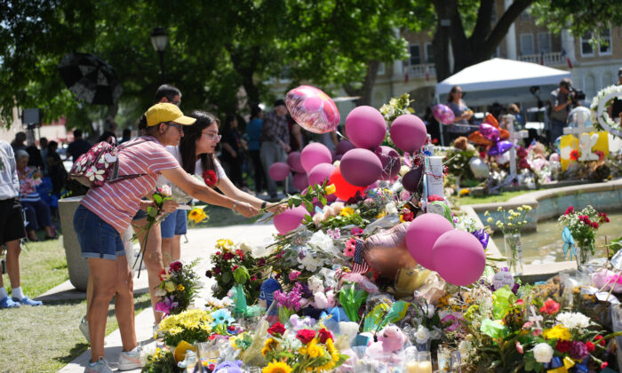 La gente coloca flores en un memorial improvisado para las 21 víctimas de un tiroteo masivo en una escuela primaria, en la plaza del pueblo de Uvalde, Texas, el 29 de mayo de 2022. (Charlotte Cuthbertson/The Epoch Times)
