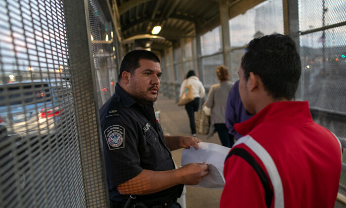 Oficial de Aduanas y Protección Fronteriza de Estados Unidos revisa los documentos de inmigración mientras un solicitante de asilo hondureño llega al puente internacional de México a Estados Unidos junto a la ciudad fronteriza de Matamoros, México, el 9 de diciembre de 2019.  (John Moore/Getty Images)