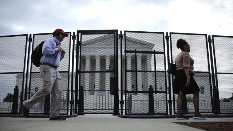 La gente camina junto a la cerca que se erigió alrededor del edificio de la Corte Suprema en Washington el 5 de mayo de 2022. (Win McNamee/Getty Images)