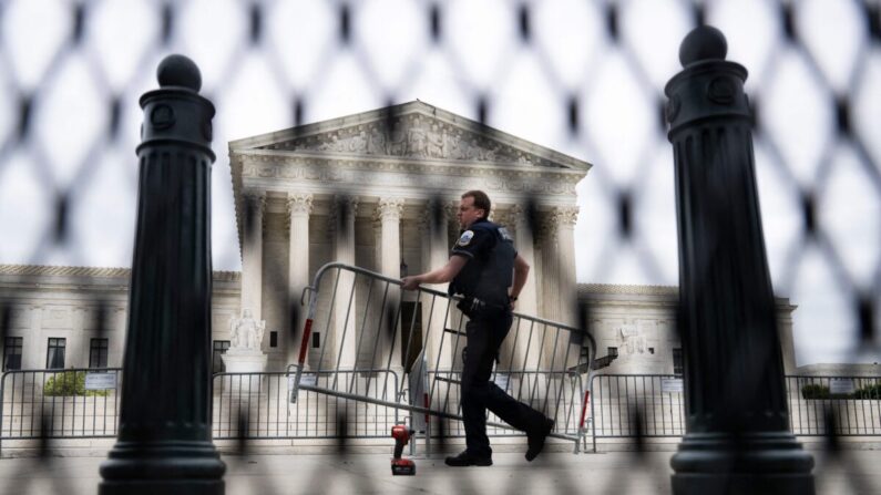 Un oficial de policía que lleva una barricada se ve a través de la valla no escalable que se encuentra alrededor de la Corte Suprema de Estados Unidos en Washington, DC, el 5 de mayo de 2022. (JIM WATSON/AFP vía Getty Images)
