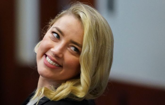 La actriz Amber Heard sonríe después de regresar de un descanso durante el juicio por difamación contra su ex marido Johnny Depp en el Tribunal de Circuito del Condado de Fairfax en Fairfax, Virginia, el 18 de mayo de 2022. (KEVIN LAMARQUE/POOL/AFP vía Getty Images)