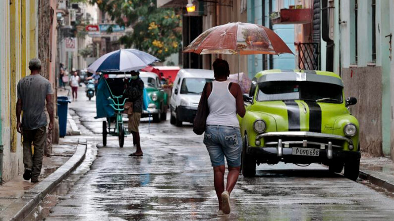 Personas se protegen de las lluvias en La Habana (Cuba). EFE/ Ernesto Mastrascusa