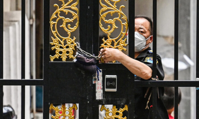Un trabajador de seguridad cierra una puerta con una cadena en un barrio bajo confinamiento por COVID-19, en el distrito de Jing'an de Shanghai, el 2 de junio de 2022. (Hector Retamal/AFP vía Getty Images)
