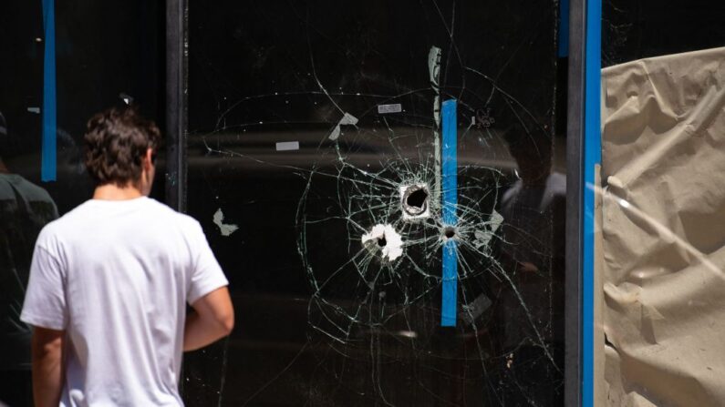 Un peatón pasa junto a los agujeros de bala en el escaparate de una tienda en South Street en Filadelfia, Pensilvania, el 5 de junio de 2022. (Kriston Jae Bethel/AFP via Getty Images)