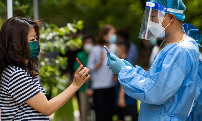 Un trabajador de la salud escanea el código de salud de una residente local para obtener los resultados de la prueba de COVID-19, en el distrito de Pudong de Shanghai, el 11 de junio de 2022. (Liu Jin/AFP vía Getty Images)
