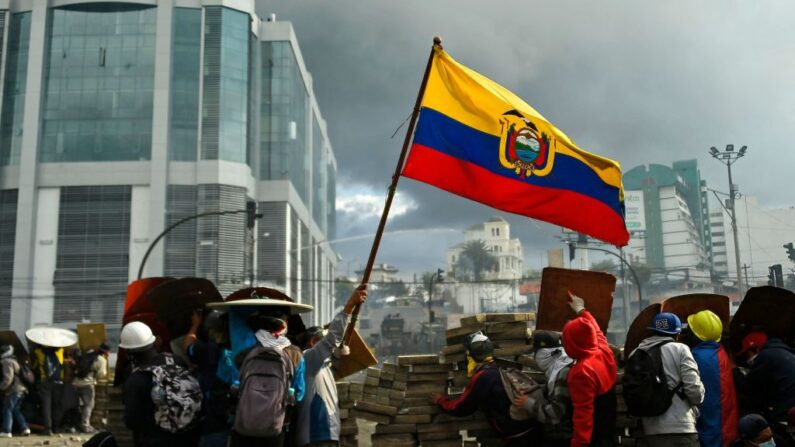 Manifestantes ondean una bandera ecuatoriana durante los enfrentamientos con la policía antidisturbios en los alrededores del parque El Arbolito, en Quito (Ecuador), el 24 de junio de 2022, en el marco de las protestas lideradas por los indígenas contra el Gobierno. (Rodrigo Buendia/AFP vía Getty Images)