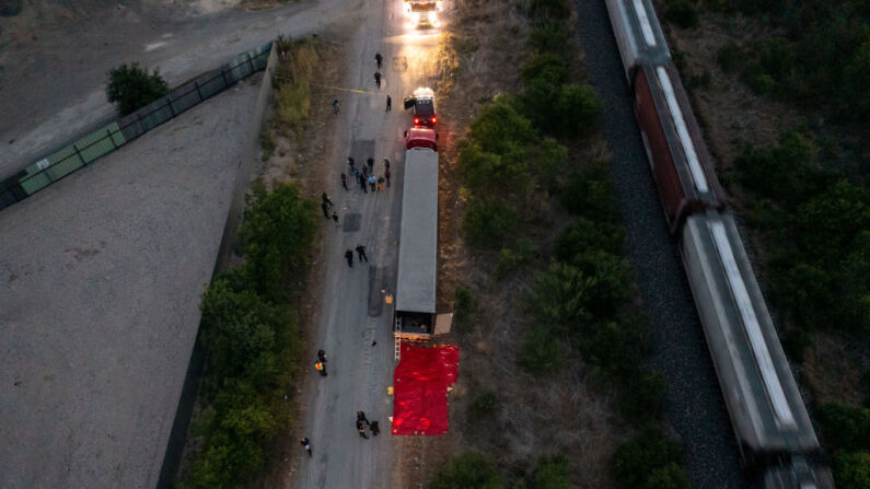Una foto aérea muestra a miembros de las fuerzas del orden investigando la causa de múltiples muertes dentro de un tráiler, el 27 de junio de 2022, en San Antonio, Texas. (Jordan Vonderhaar/Getty Images)