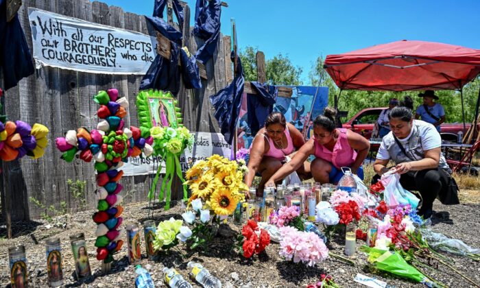 Unas personas colocan flores y velas en un memorial improvisado en donde se descubrió un tractor-remolque con migrantes en su interior, a las afueras de San Antonio, Texas, el 29 de junio de 2022. (Chandan Khanna/AFP a través de Getty Images)