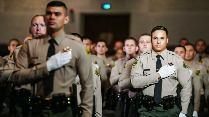 Los graduados de la clase 451 de la Academia del Departamento del Sheriff del Condado de Los Ángeles se ponen de pie para el juramento de lealtad en su ceremonia de graduación en el East Los Angeles College en medio de la pandemia de COVID-19 en Monterey Park, California, el 21 de agosto de 2020. (Mario Tama/Getty Images)
