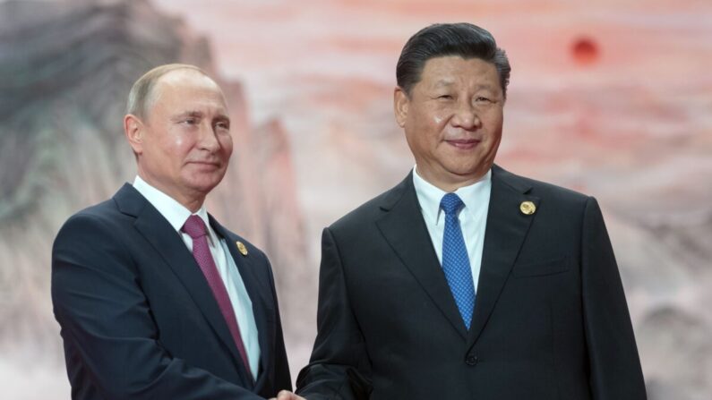 El presidente ruso Vladimir Putin (izq.) estrecha la mano del líder chino Xi Jinping durante una ceremonia de bienvenida en el Consejo de Jefes de Estado de la Organización de Cooperación de Shanghái en Qingdao, China, el 10 de junio de 2018. (Sergei Guneyev/Sputnik/AFP vía Getty Images)
