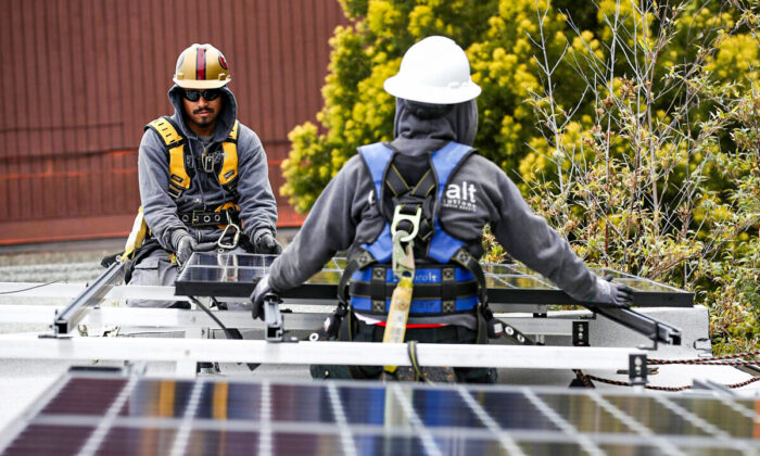 Los instaladores solares de Luminalt, Pam Quan (derecha) y Walter Morales, instalan paneles solares en el techo de una casa, en San Francisco, el 9 de mayo de 2018. (Justin Sullivan/Getty Images)
