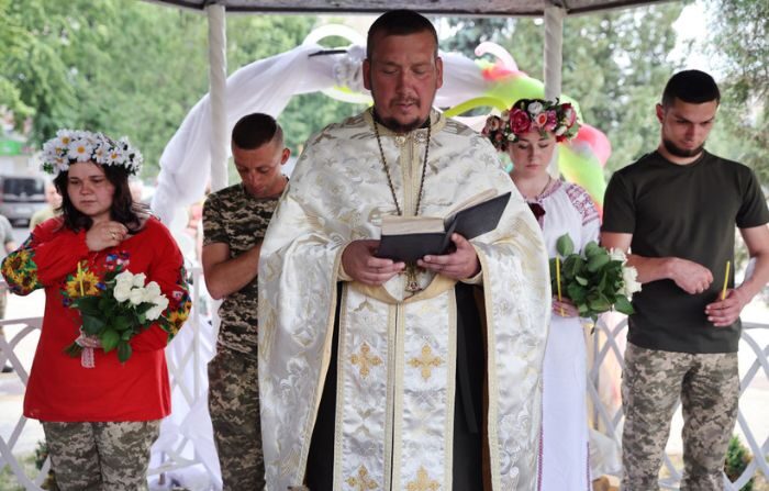 Los soldados Vitalii Orlich y su novia Kristina (D) y Volodymyr Mykhailuk y su novia Hrystyna se casan durante una ceremonia de boda conjunta el 12 de junio de 2022 en Druzhkivka, Donetsk Oblast, Ucrania. (Scott Olson/Getty Images)