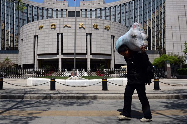 Un trabajador migrante chino pasa junto al Banco Popular de China en Beijing el 1 de mayo de 2013. El Banco Popular publicó la "Ley de Estabilidad Financiera (Borrador para Comentarios)" el 6 de abril de 2022, diciendo que resolver los riesgos financieros es un "tema constante". (Mark Ralston/AFP/Getty Images)