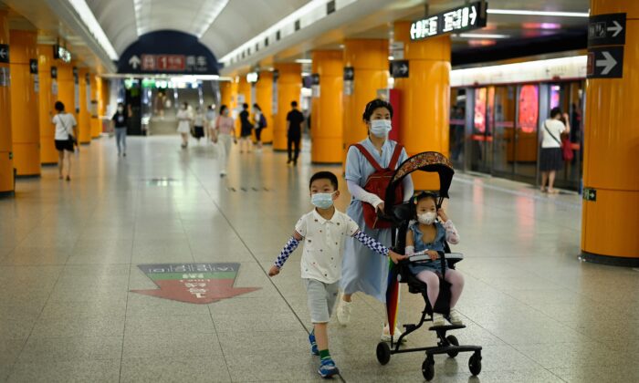 Una mujer camina en una estación de metro con dos niños en Beijing, el 5 de julio de 2022. (WANG ZHAO/AFP a través de Getty Images)