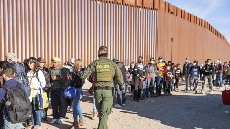 Un agente de la Patrulla Fronteriza organiza a los inmigrantes ilegales que se han reunido junto a la valla fronteriza tras cruzar desde México a Estados Unidos en Yuma, Arizona, el 10 de diciembre de 2021. (Charlotte Cuthbertson/The Epoch Times)
