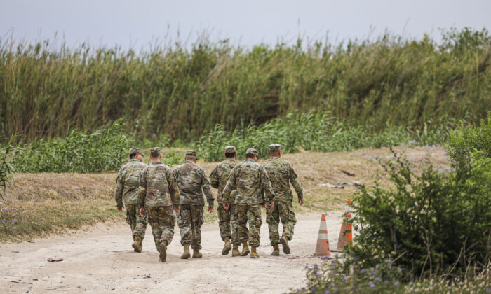 Un grupo de miembros de la Guardia Nacional de Texas camina hacia un grupo de cubanos que cruzaron ilegalmente el Río Bravo, desde México hacia Eagle Pass, Texas, el 19 de abril de 2022. (Charlotte Cuthbertson/The Epoch Times)
