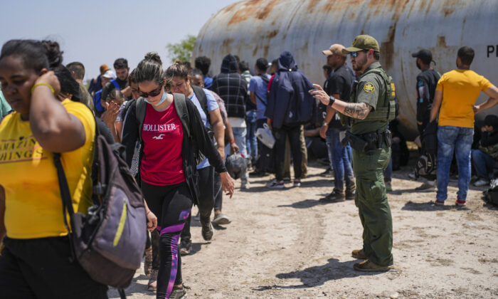 Agente de la Patrulla Fronteriza organiza un gran grupo de inmigrantes ilegales cerca de Eagle Pass, Texas, el 20 de mayo de 2022. (Charlotte Cuthbertson/The Epoch Times)