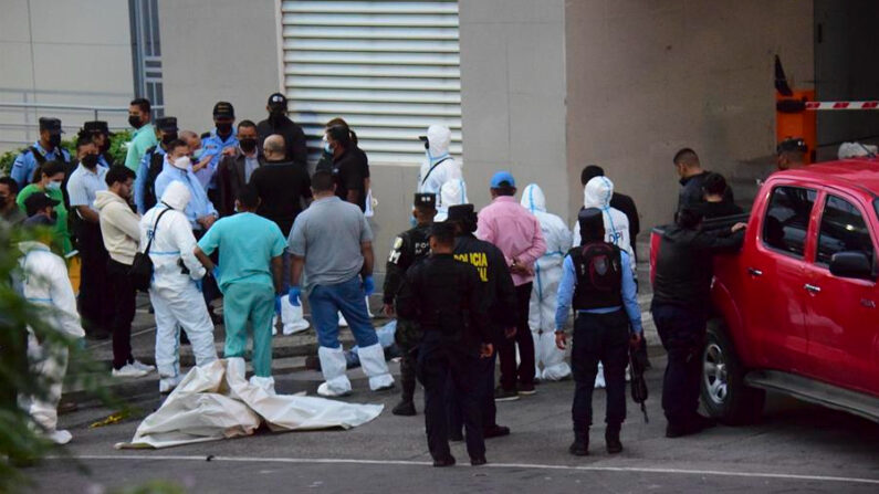 Policías y expertos forenses realizan el levantamiento de cuatro personas asesinadas en la madrugada de este jueves, a la salida del estacionamiento de un edificio donde funcionan locales comerciales y residenciales, en Tegucigalpa (Honduras). EFE/ STR