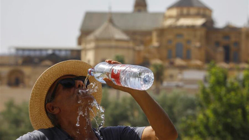 Un turista toma agua ante la Mezquita-Catedral de Córdoba (España) para combatir la ola de calor el 16 de julio de 2022. EFE/Salas