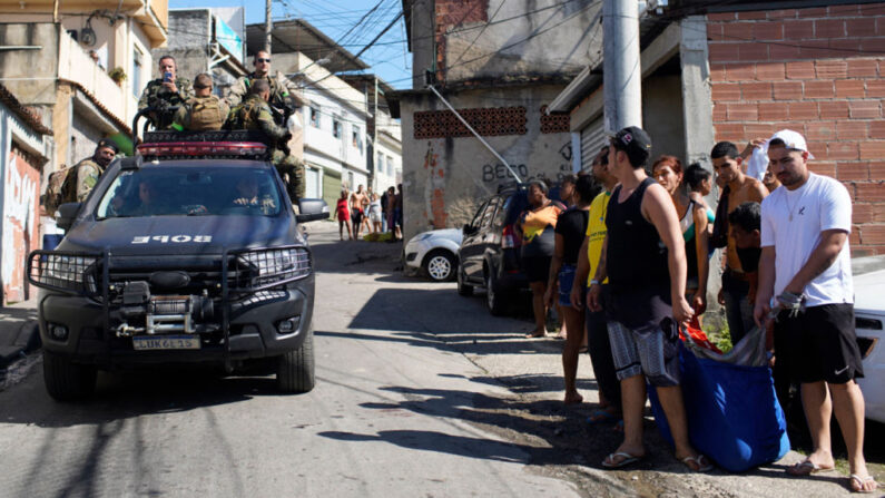 Un camión de la policía pasa junto a los residentes de la favela Complexo do Alemao llevando el cadáver de un hombre muerto durante una redada policial en Río de Janeiro, Brasil, el 21 de julio de 2022. (Mauro Pimentel/AFP vía Getty Images)