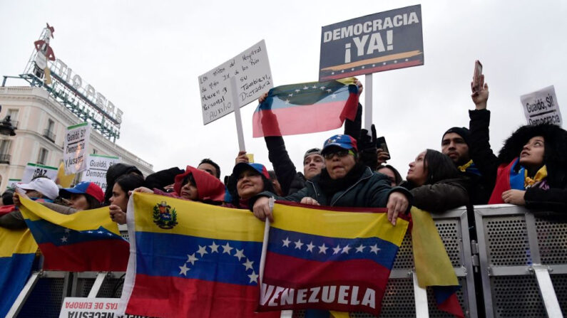 Venezolanos residentes en España sostienen carteles con la leyenda "¡Democracia ya!" y banderas de Venezuela durante una manifestación en Madrid el 25 de enero de 2020. (Javier Soriano/AFP vía Getty Images)