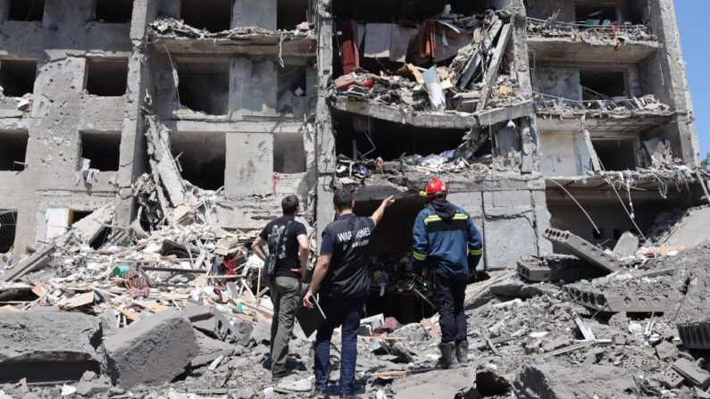 Un fiscal de crímenes de guerra (centro), un socorrista (derecha) y un civil observan un edificio destruido tras ser alcanzado por un ataque con misiles en la ciudad ucraniana de Sergiyvka, cerca de Odessa, que causó la muerte de al menos 18 personas y 30 heridos, el 1 de julio de 2022. (Oleksandr Gimanov/AFP vía Getty Images)