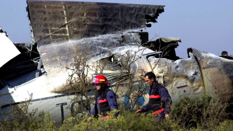 En una fotografía de archivo, dos efectivos de bomberos pasan frente a restos de un avión militar, el 17 de mayo de 2001, en el aeropuerto de la provincia de Mendoza, Argentina. (Walter Moreno/AFP vía Getty Images)