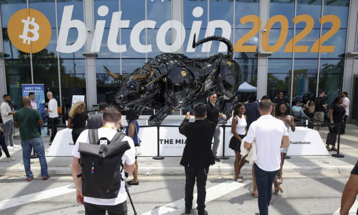 Los asistentes posan para fotos frente a The Miami Bull durante la Conferencia Bitcoin 2022 en el Centro de Convenciones de Miami Beach, el 7 de abril de 2022. (Marco Bello/Getty Images)