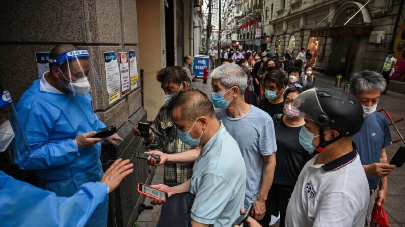 Unos trabajadores escanean los códigos sanitarios QR de las personas que entran en un centro comercial en el distrito de Huangpu, en Shanghái, el 1 de junio de 2022. (Hector Retamal/AFP vía Getty Images)
