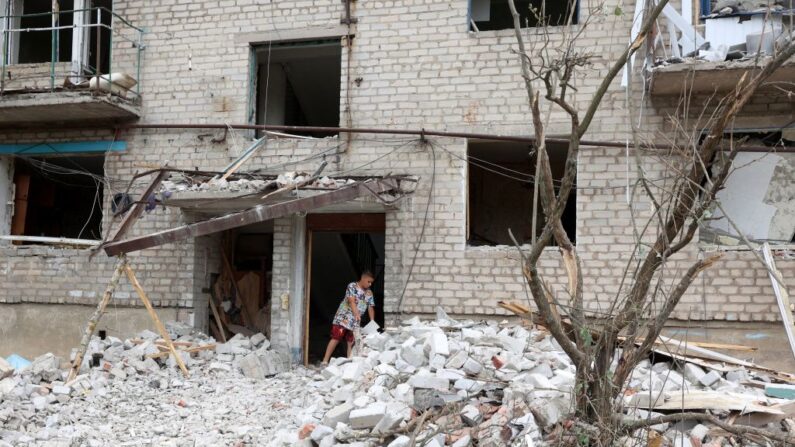 Un niño, residente local, saca la basura de un edificio parcialmente destruido tras un bombardeo en Chasiv Yar, este de Ucrania, el 10 de julio de 2022. (Anatolii Stepanov/AFP vía Getty Images)