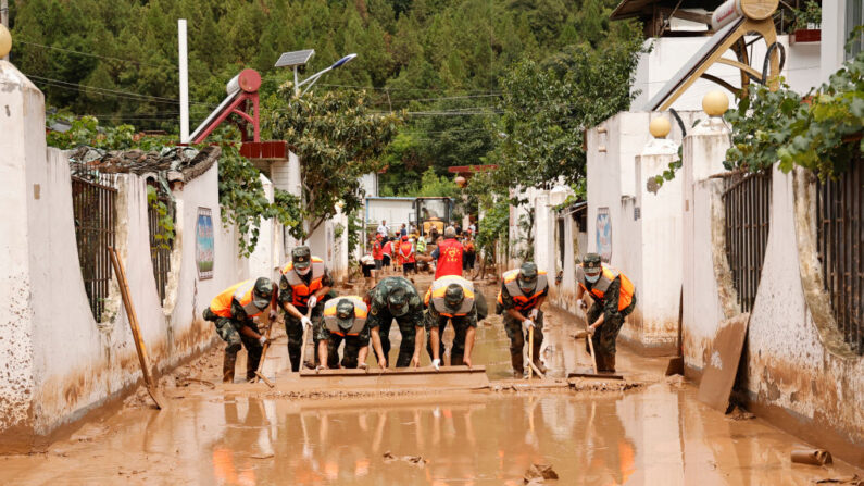Esta foto tomada el 16 de julio de 2022 muestra a policías paramilitares limpiando una calle tras las inundaciones en Longnan, en la provincia noroccidental china de Gansu (China). (STR/AFP vía Getty Images)