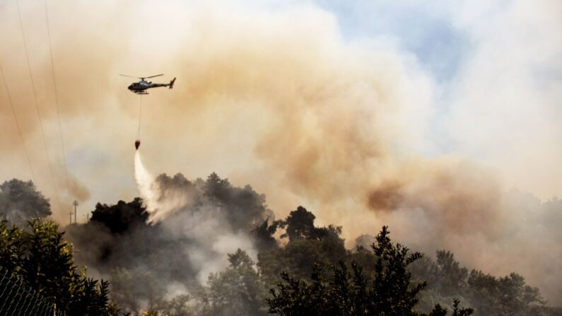 Un helicóptero lanza agua sobre un incendio forestal que arrasa cerca de la ciudad de Massarosa, región de la Toscana, en el centro de Italia, el 20 de julio de 2022. (Federico Scoppa/AFP vía Getty Images)