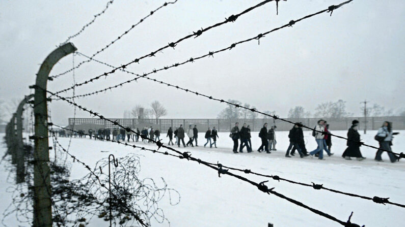 Visitantes caminan a lo largo de la valla del antiguo campo de concentración de Sachsenhausen el 27 de enero de 2004 en la ciudad oriental de Oranienburg, Alemania. (MICHAEL URBAN/DDP/AFP a través de Getty Images)